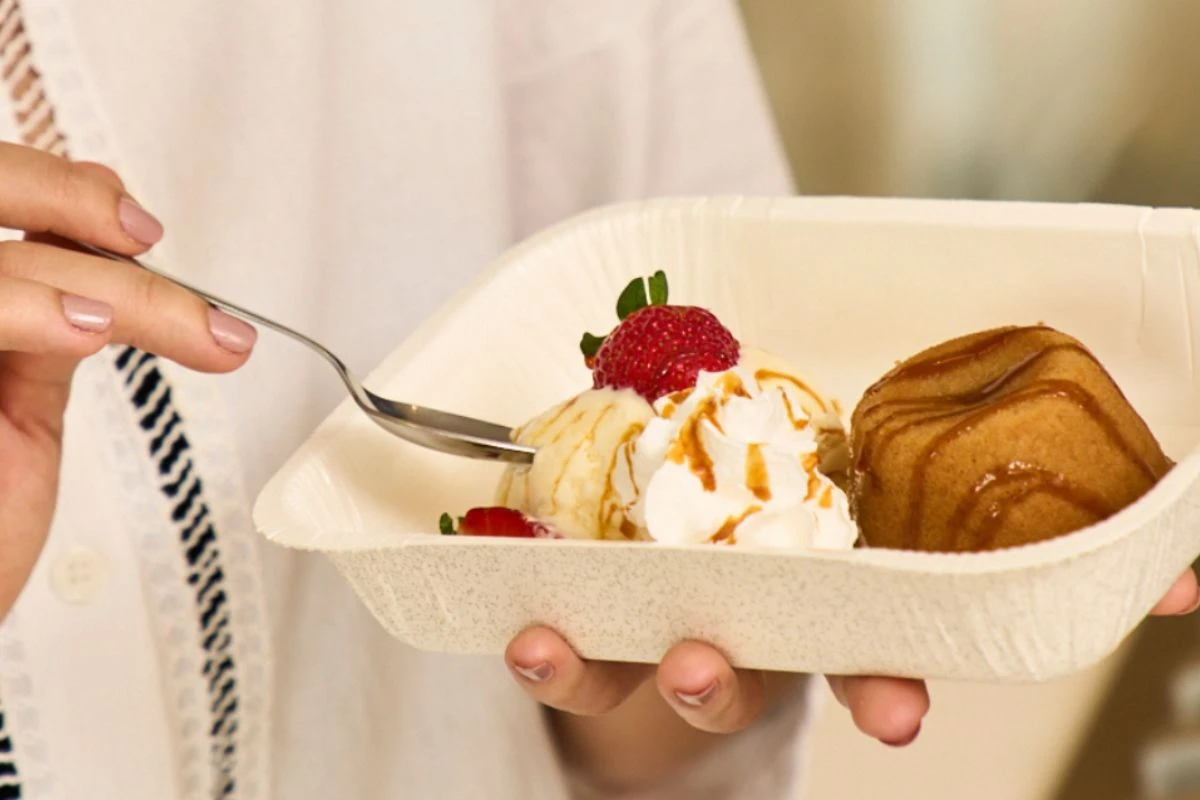 Mulher comendo sobremesa de sorvete com bolo e morango, representando o gelato e sorvete​.