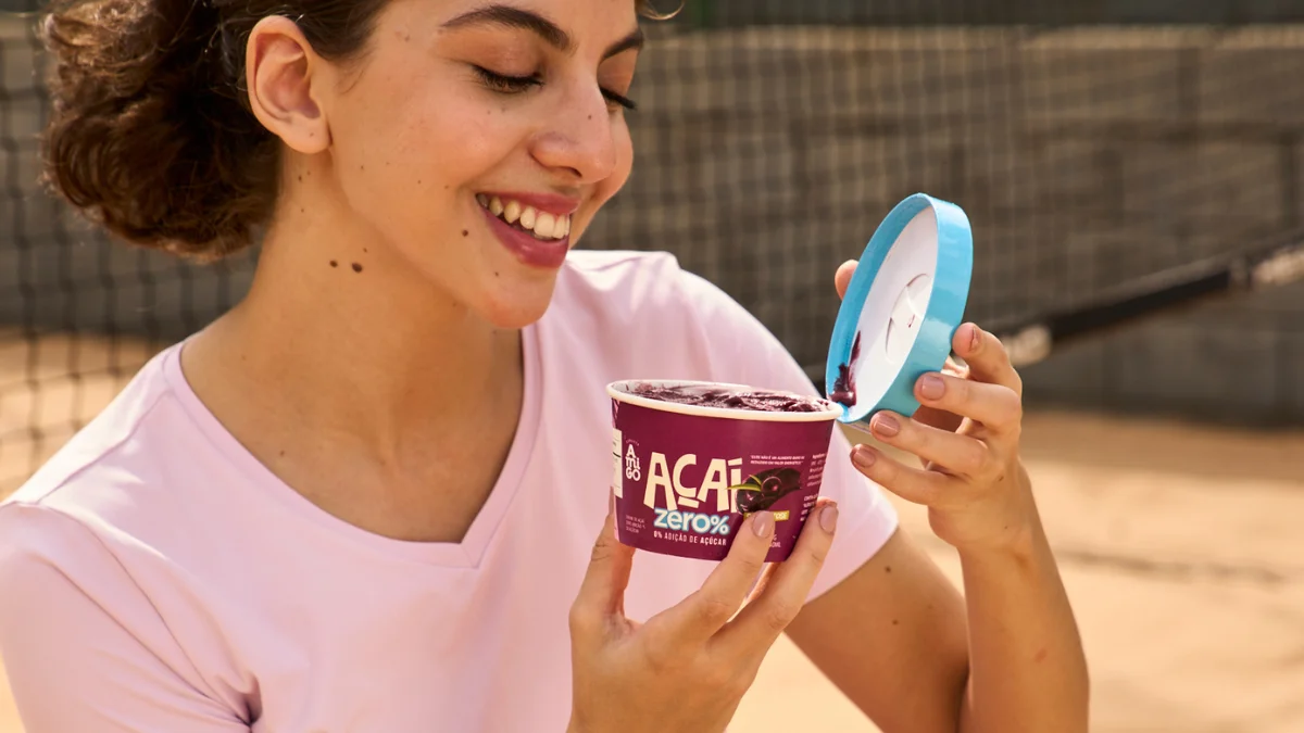 Mulher sorridente com um potinho descartável com tampa de açaí da Apolo Embalagens.