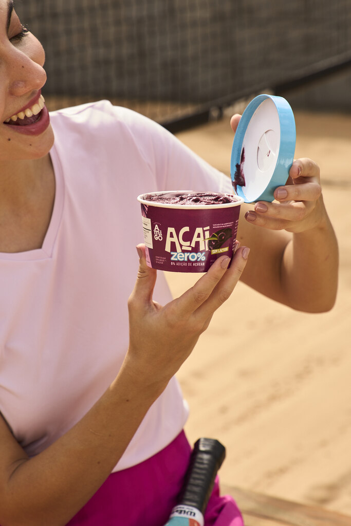 Consumidora segurando embalagem de açaí individual com tampa, destacando praticidade e conservação do produto.